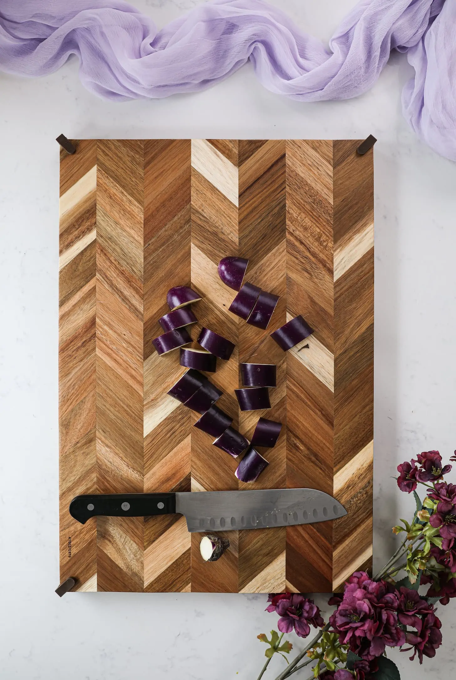 chopping board with pieces of eggplant and a knife.