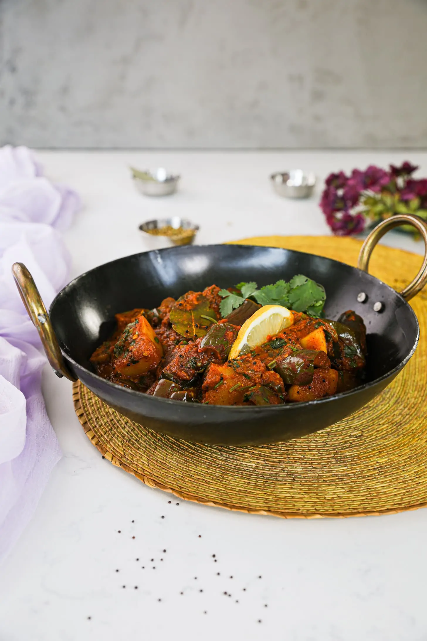 perspective shot of a wok of cooked vegetables on a yellow mat with ramekins in the background.