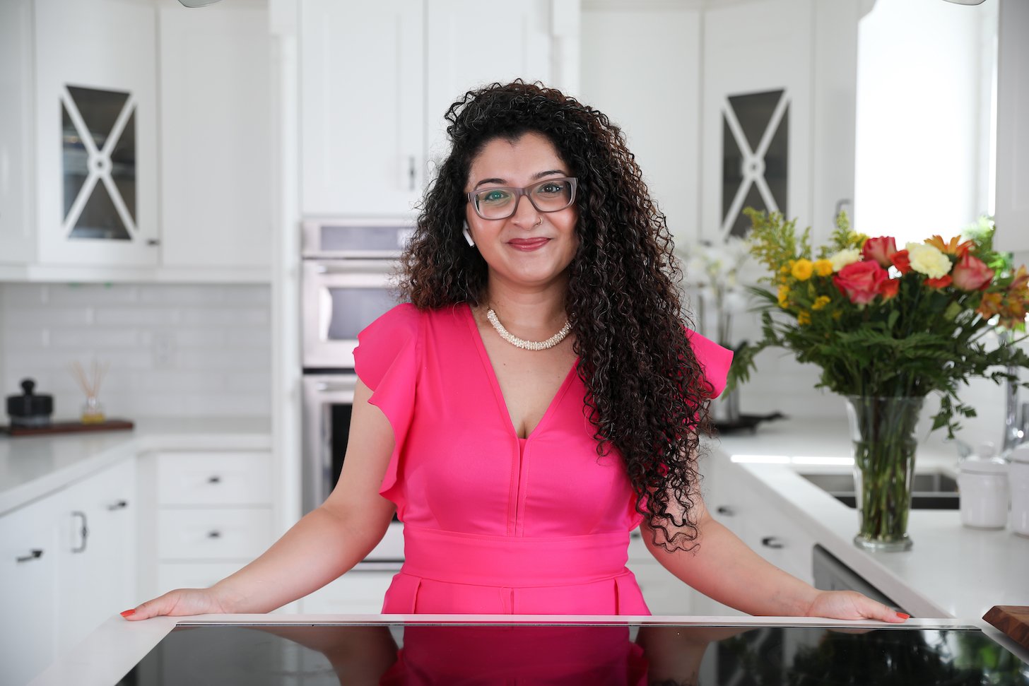 a curly haired lady in her kitchen posing for the camera.