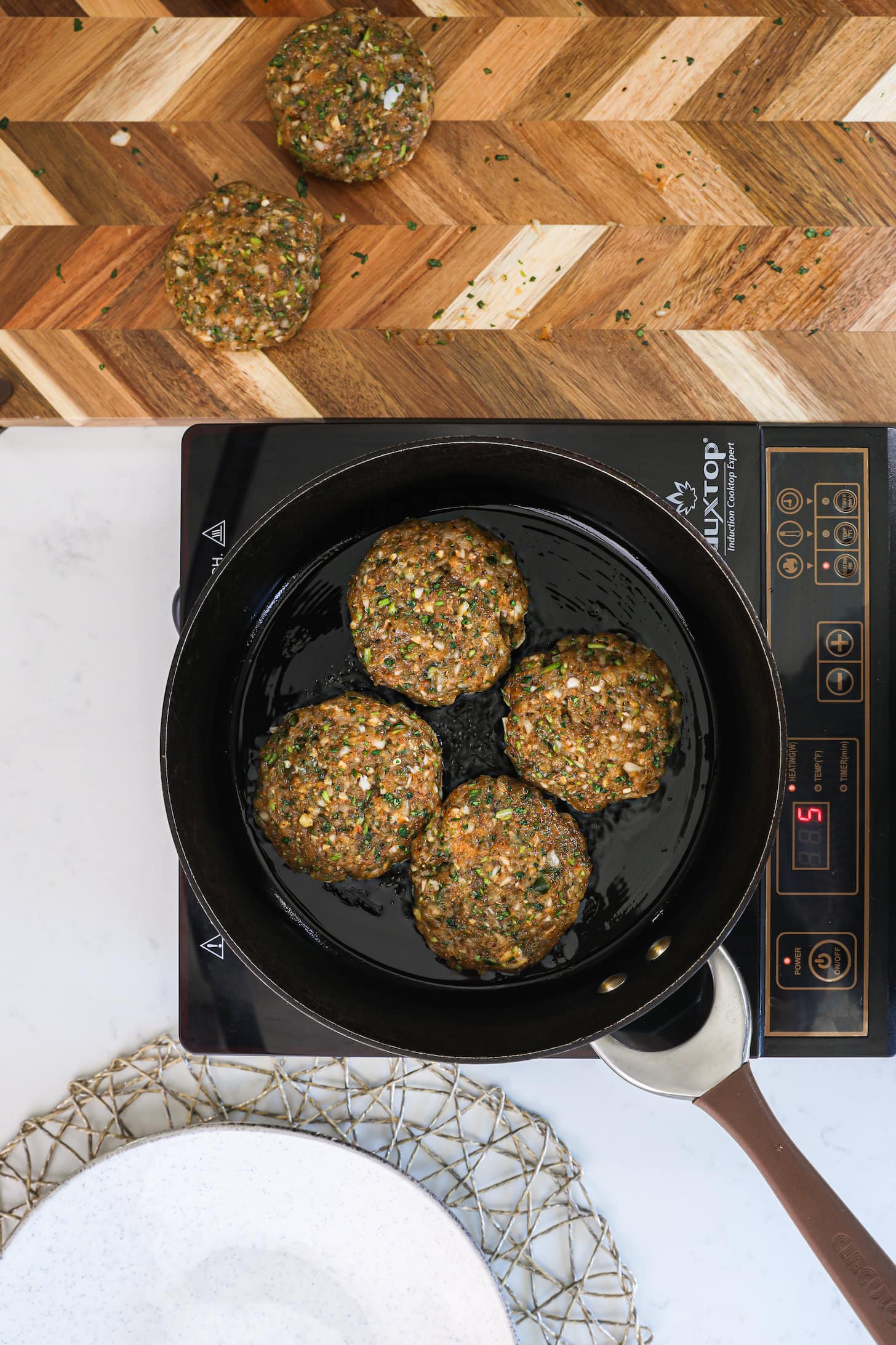 a pan of four patties on a mobile cooktop