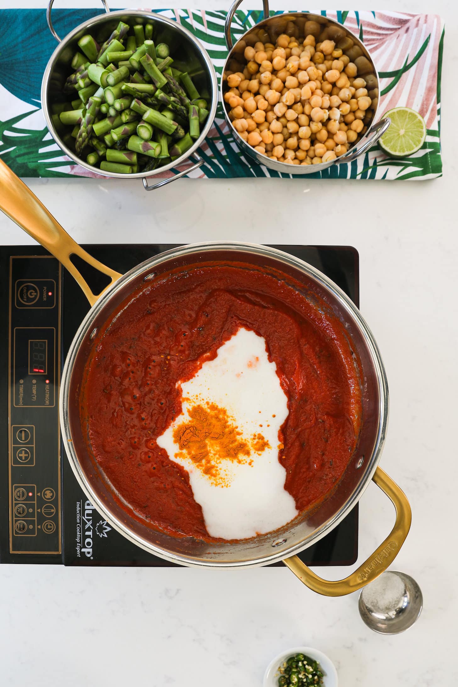 a pan of tomato sauce with a splash of white sauce and an orange powder on top.