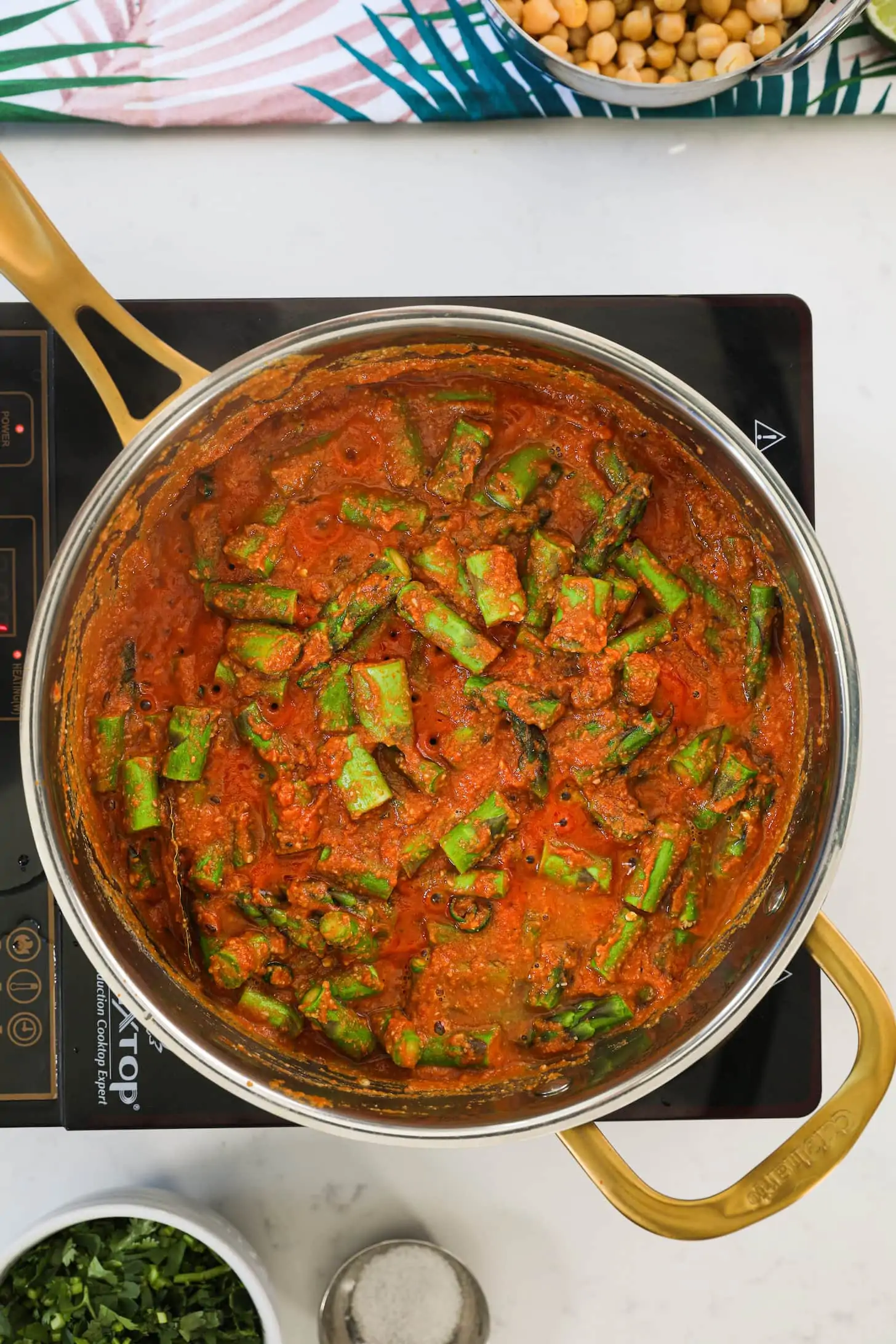 a pan of red sauce with pieces of asparagus.