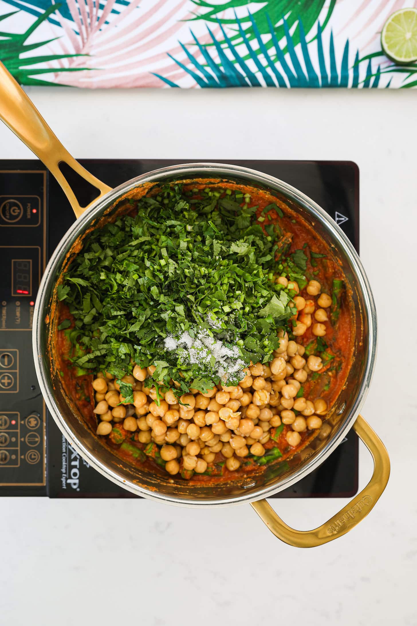 a pan of chickpeas and chopped herbs on a mobile cooktop.
