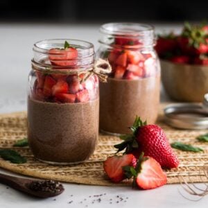 mason jars of chocolate chia pudding topped with chopped strawberries