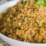 a close up of cooked quinoa with some greens embedded in it.