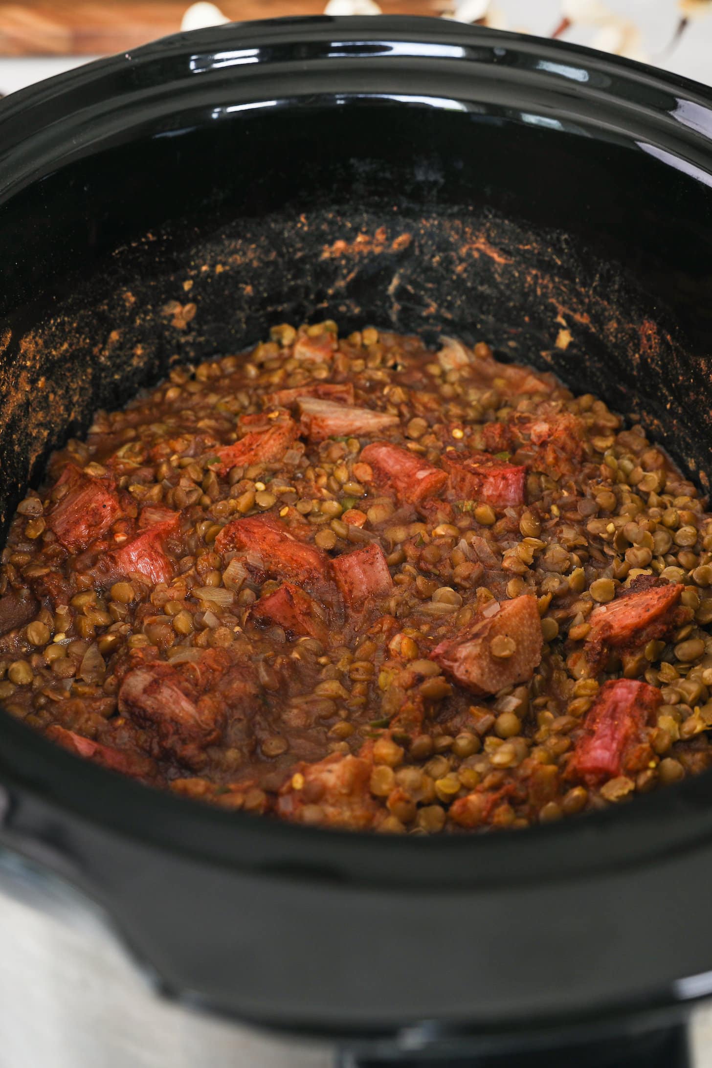 cooked lentils with chunks of rhubarb in a black pot.