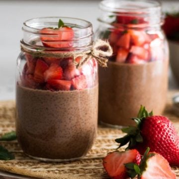 mason jars of chocolate chia pudding topped with chopped strawberries - on different planes.