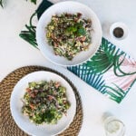 Flatlay image of two bowl of creamy salad styled with a leafy tea towel and a brown mat.