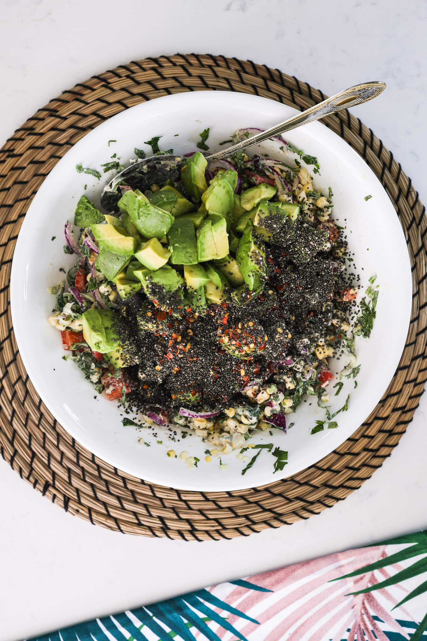 Overhead image of a bowl with avocado chunks, chia seeds and other chopped food ingredients that cannot be seen.