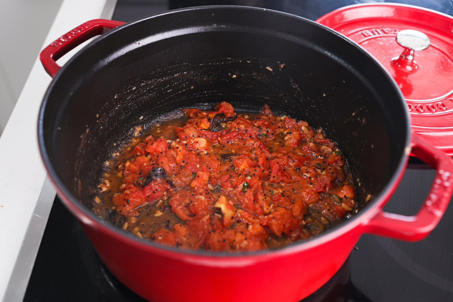 A red pot of red sauce with tiny black seeds.