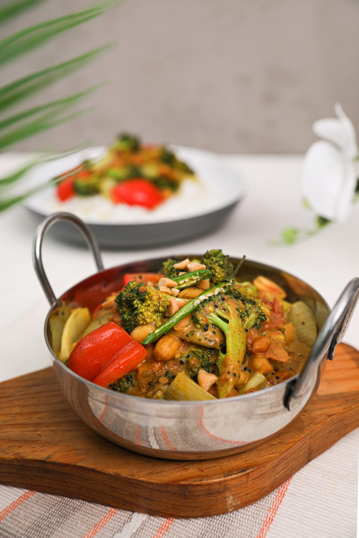 a close up image of a wok of cooked vegetables in a yellow sauce with another bowl in the background.