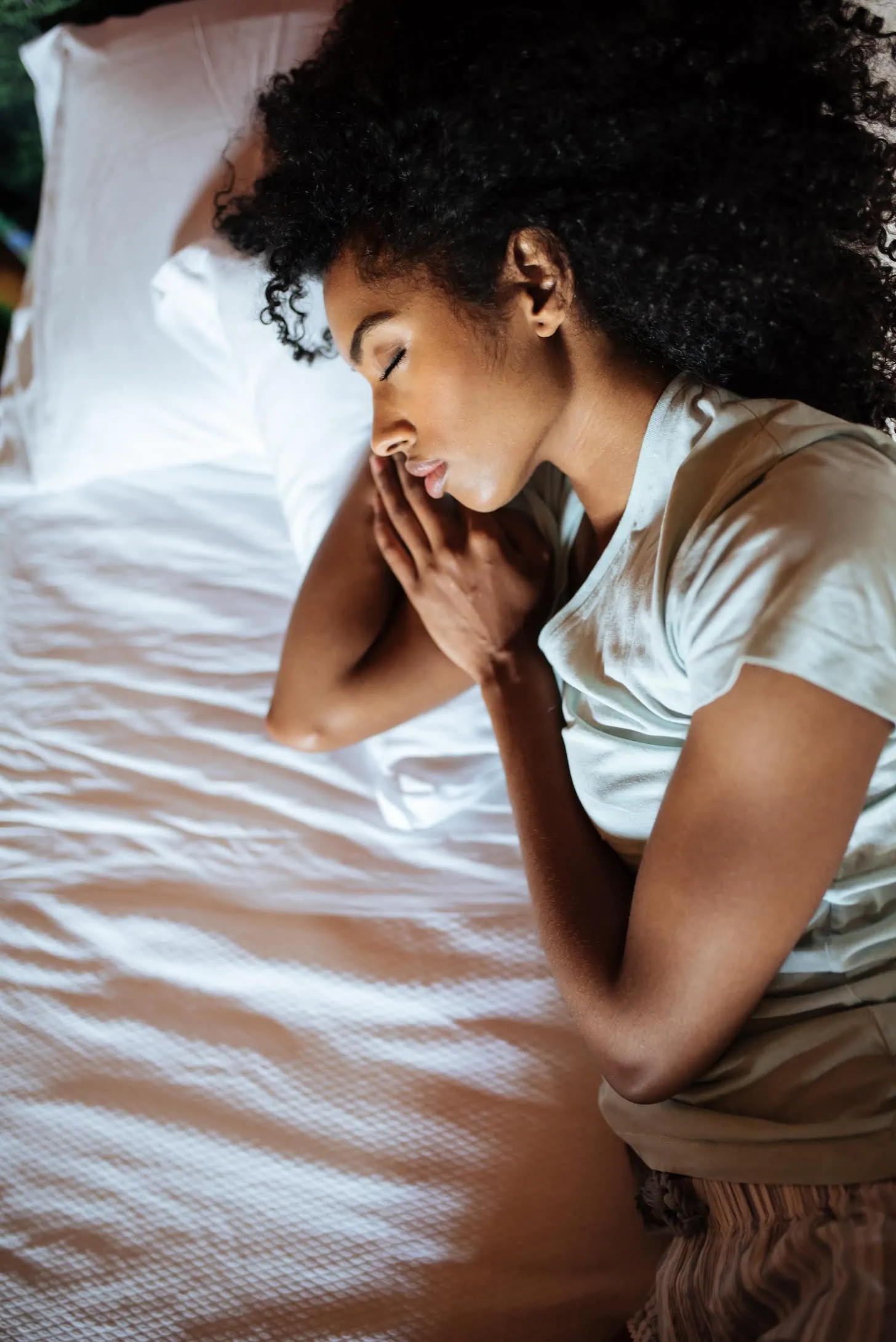 Beautiful black woman lying down in bed sleeping.