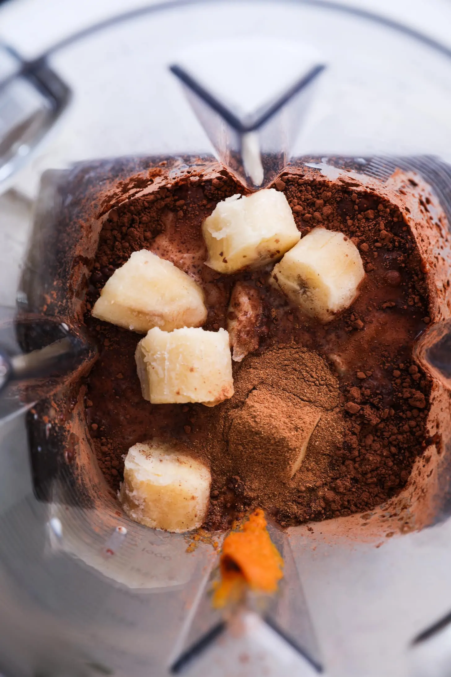 Flatlay of a container with chunks of banana and chocolate powder.