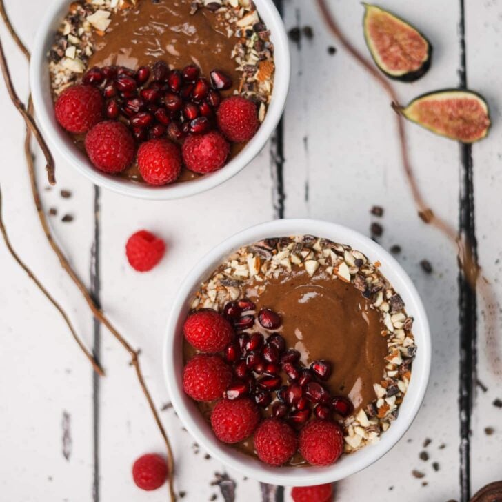 Flatlay image of a bowl of chocolate smoothie topped with nuts and berries.