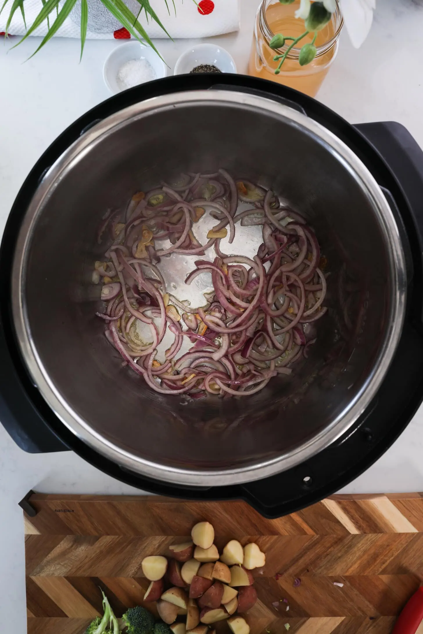 Birdseye view of Instant pot with red onion slices frying in oil.