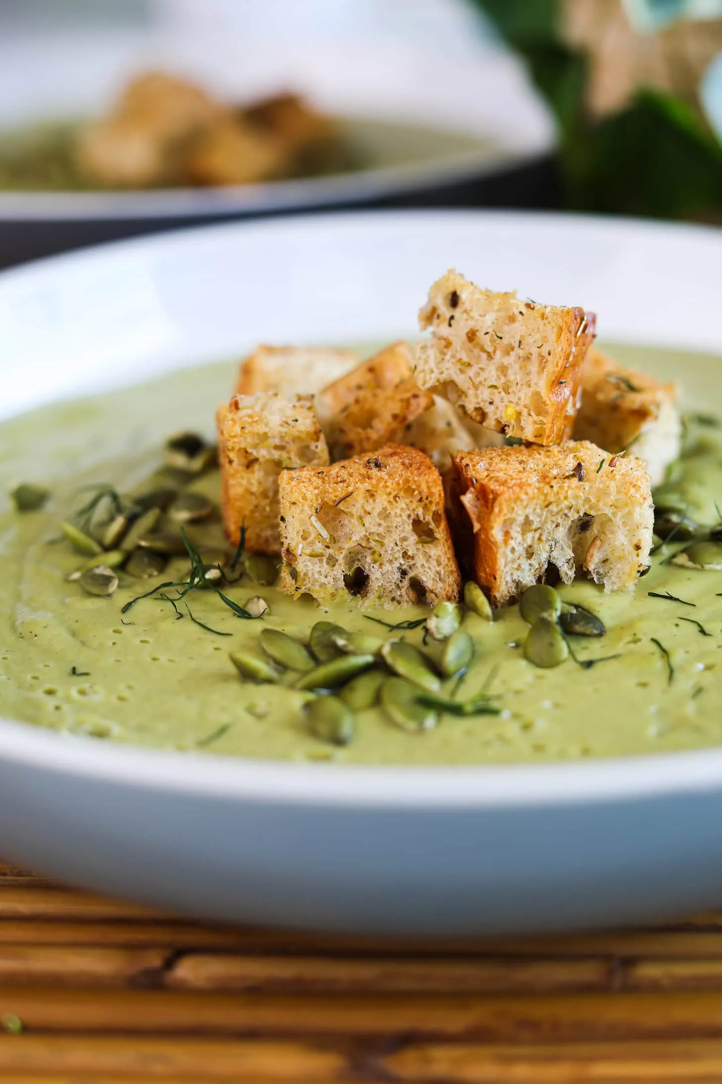 Perspective image of a heap of croutons on green soup.