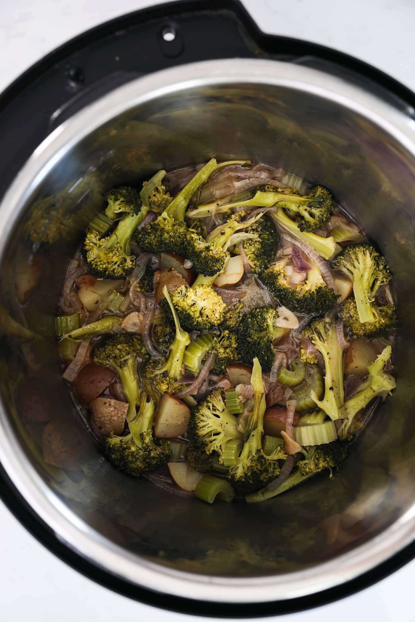 Vista panorámica de la olla instantánea con brócoli cocido y verduras.