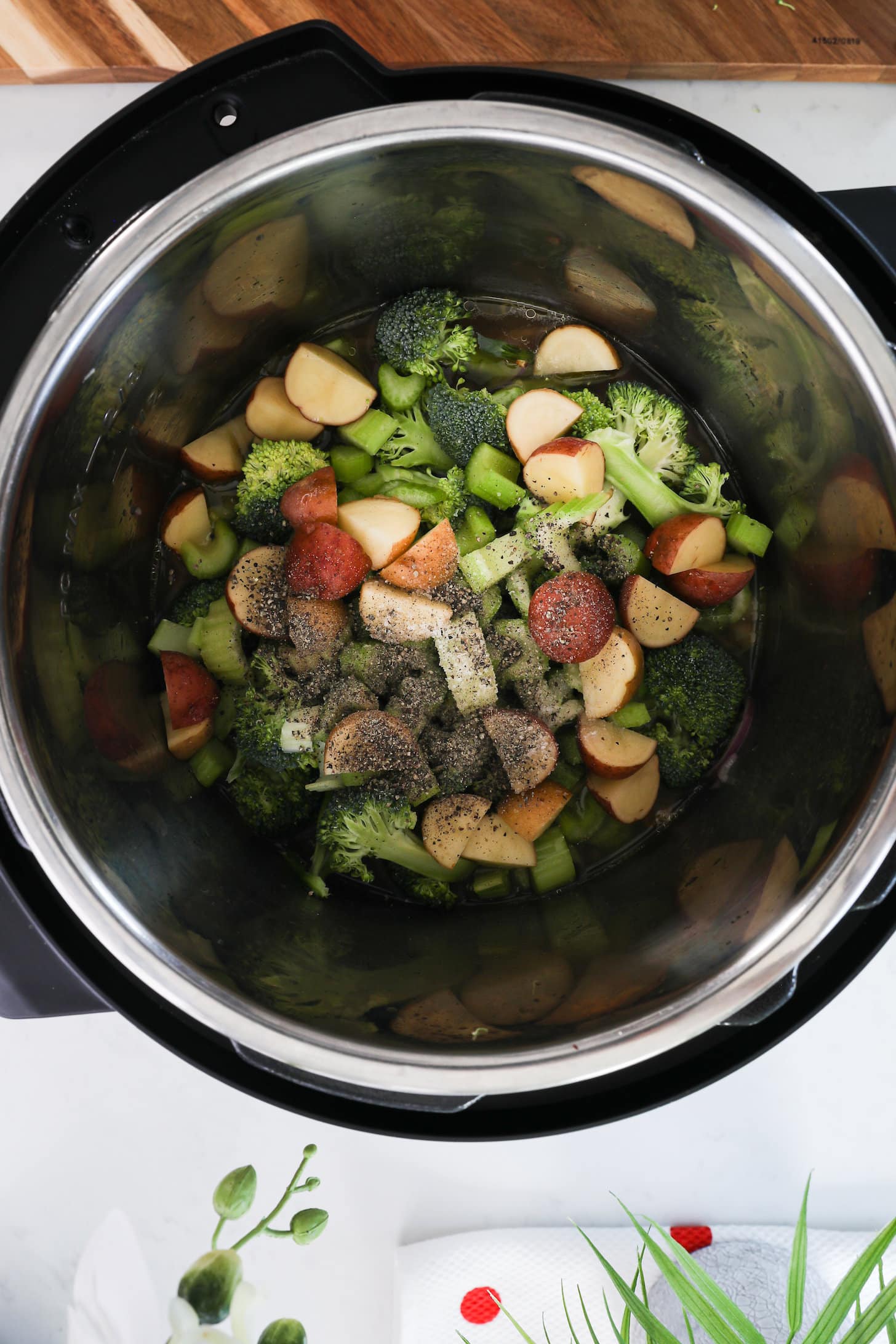 Birdseye view of Instant pot with chopped vegetables coated in pepper.