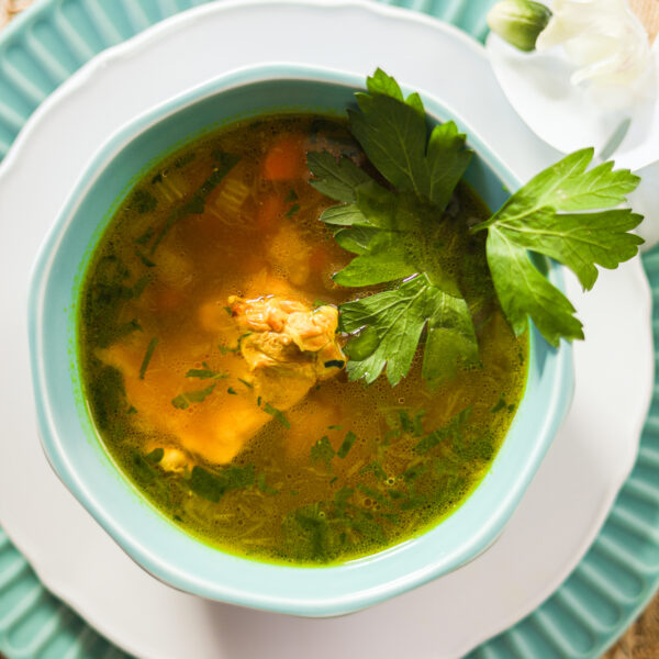 Flatlay of a bowl of brown soup on 2 plates that's topped with parsley leaf.
