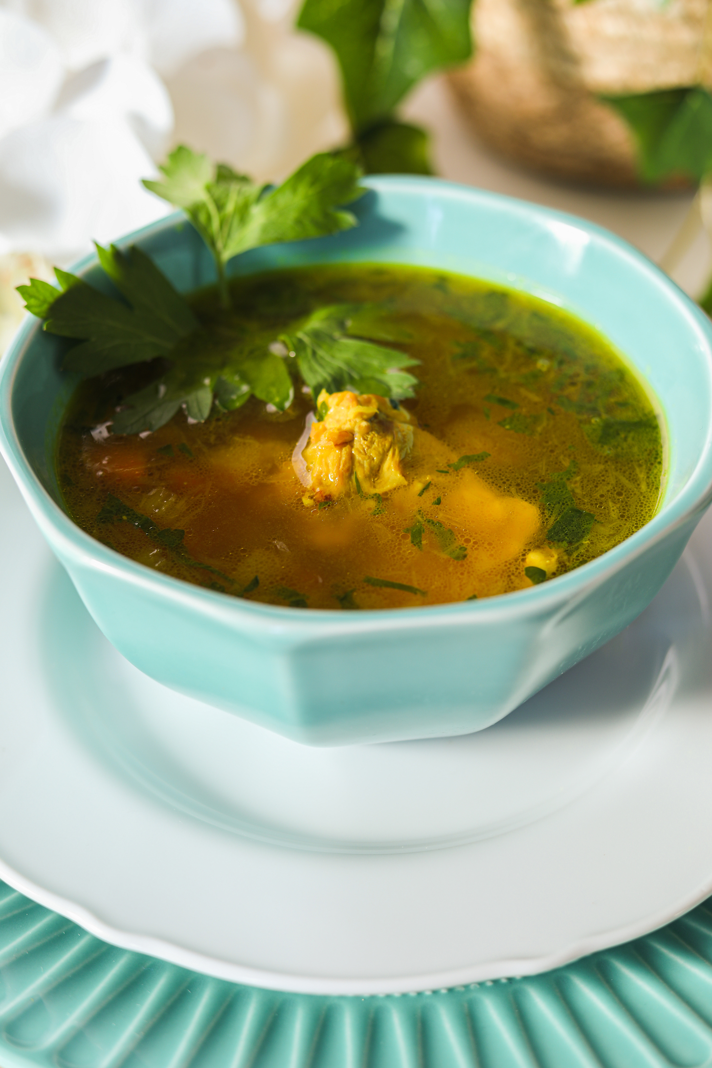 Perspective shot of a bowl of brown soup on a white plate topped with parsley leaf.