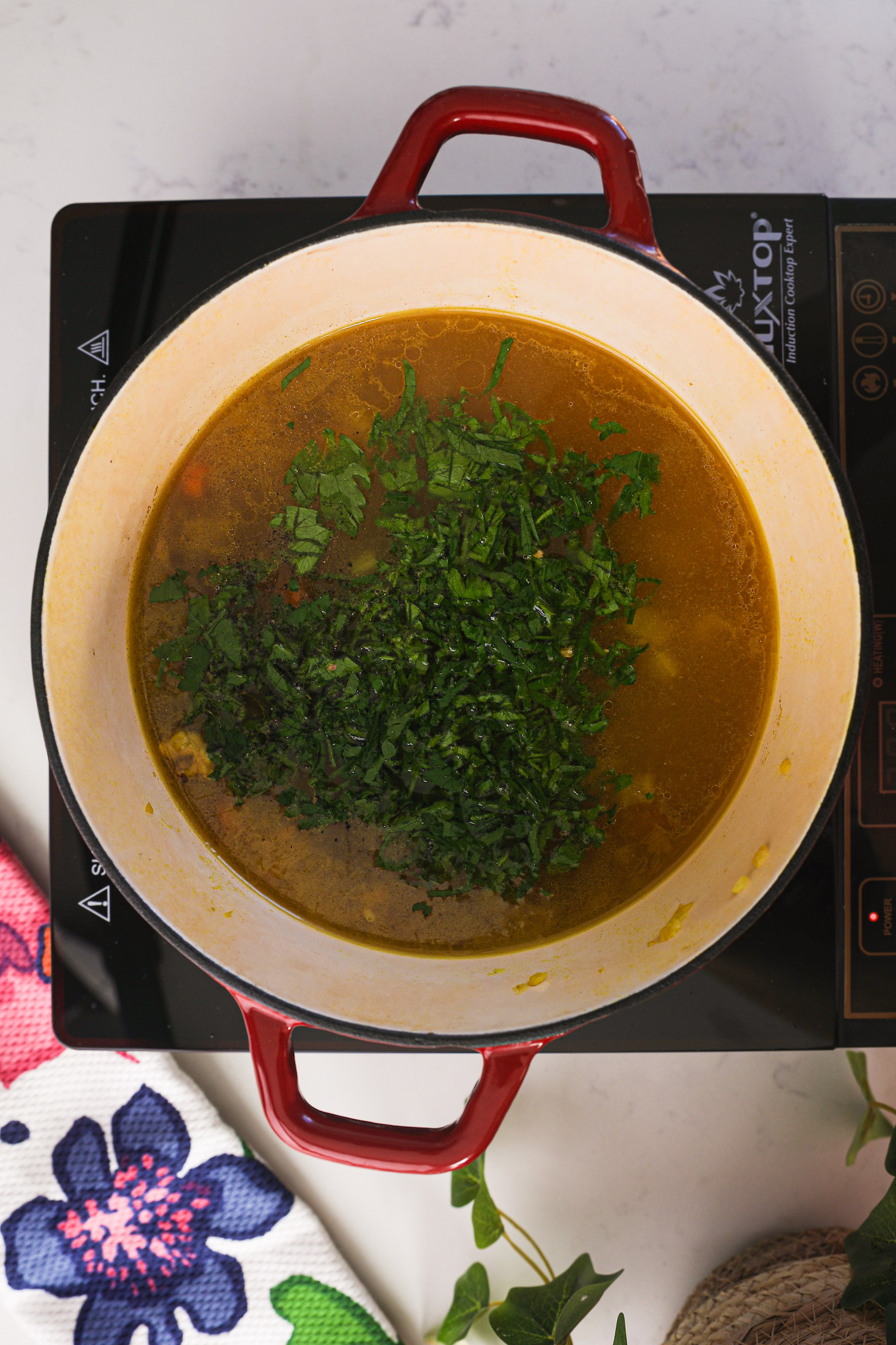 A cooking pot of broth with herbs floating on it.