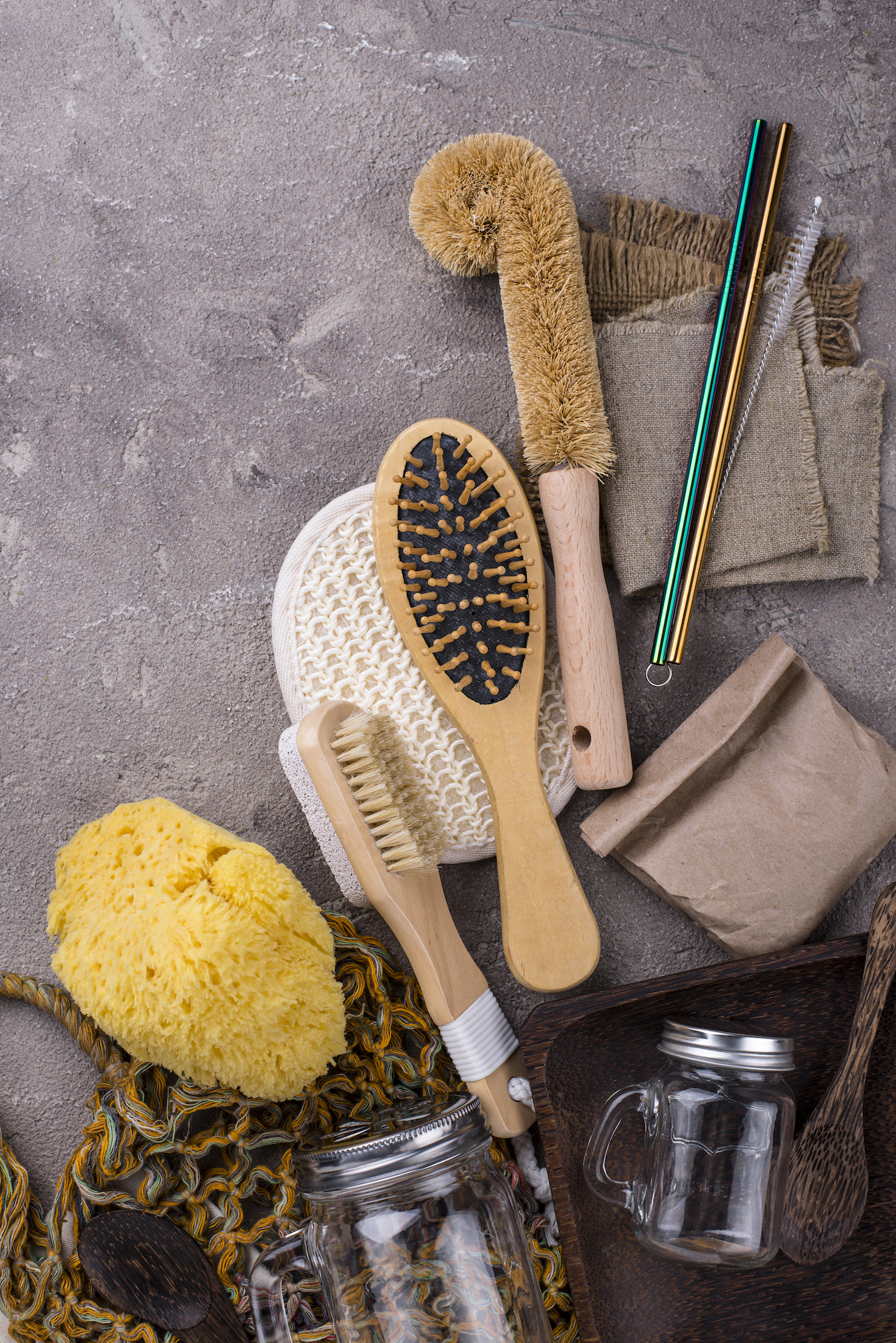 Eco-friendly home accessories for zero waste living. Soap, glass jar, comb, brush, washcloth, wicker bag, coconut tableware.