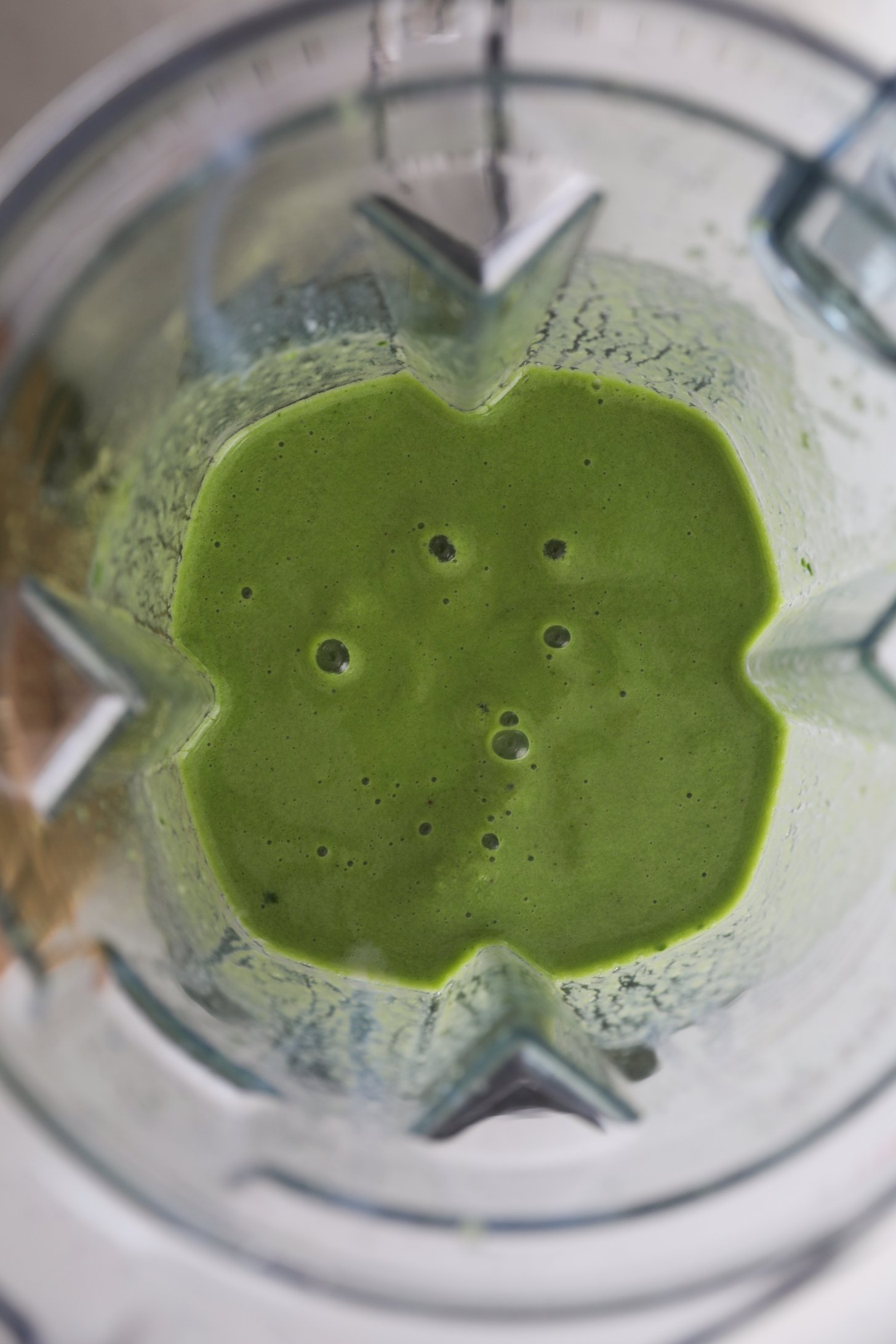 Overhead image of a blender with a green shake with bubbles.