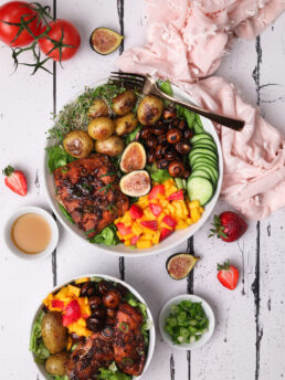 Bowls of bright salads topped with piece of fish, button mushroom, gigs and a mango-strawberries salsa.