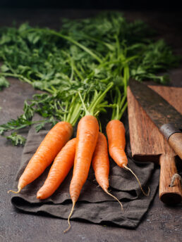 Fresh organic and sweet carrot over dark stone background.