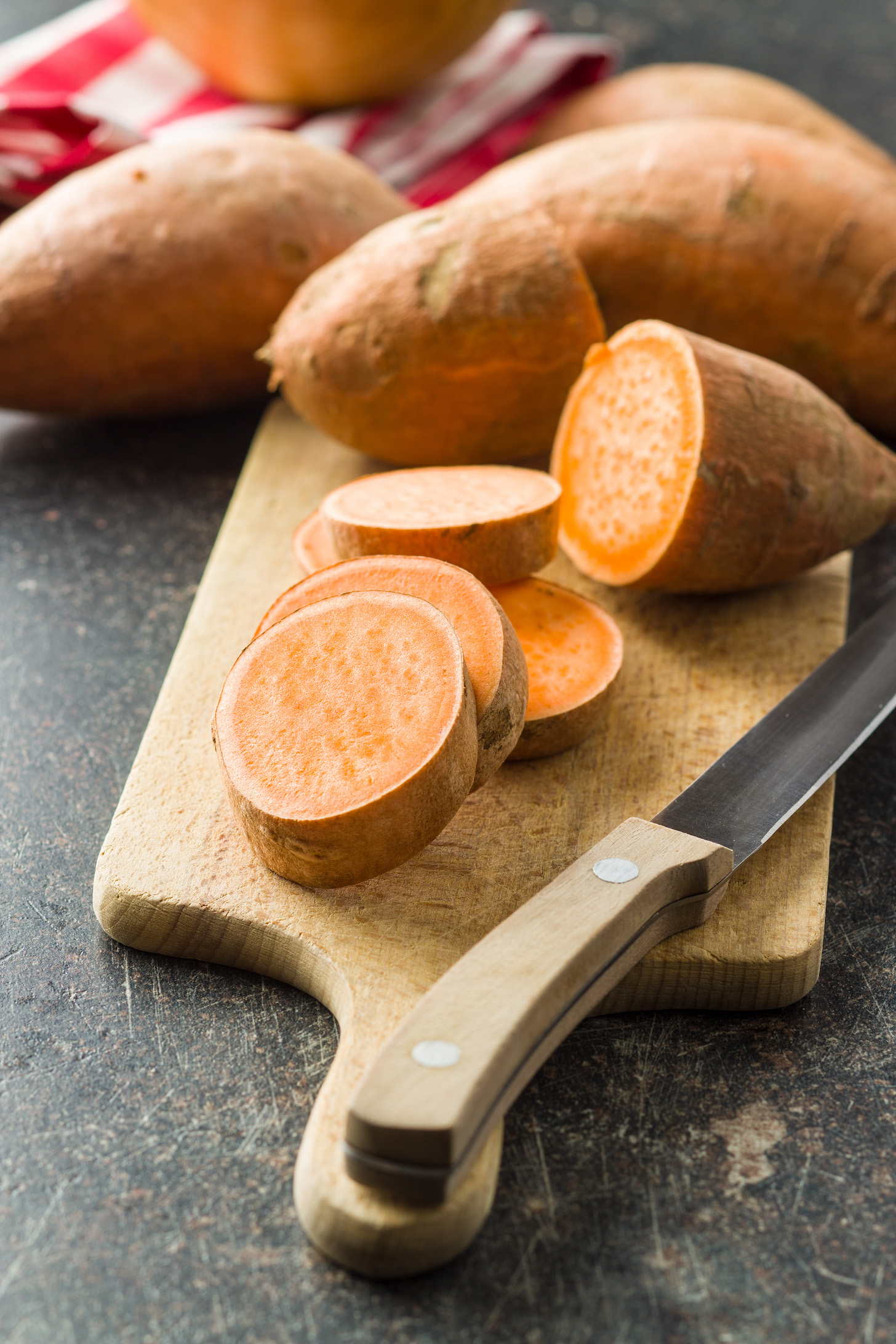 The sweet potatoes on cutting board on old kitchen table.