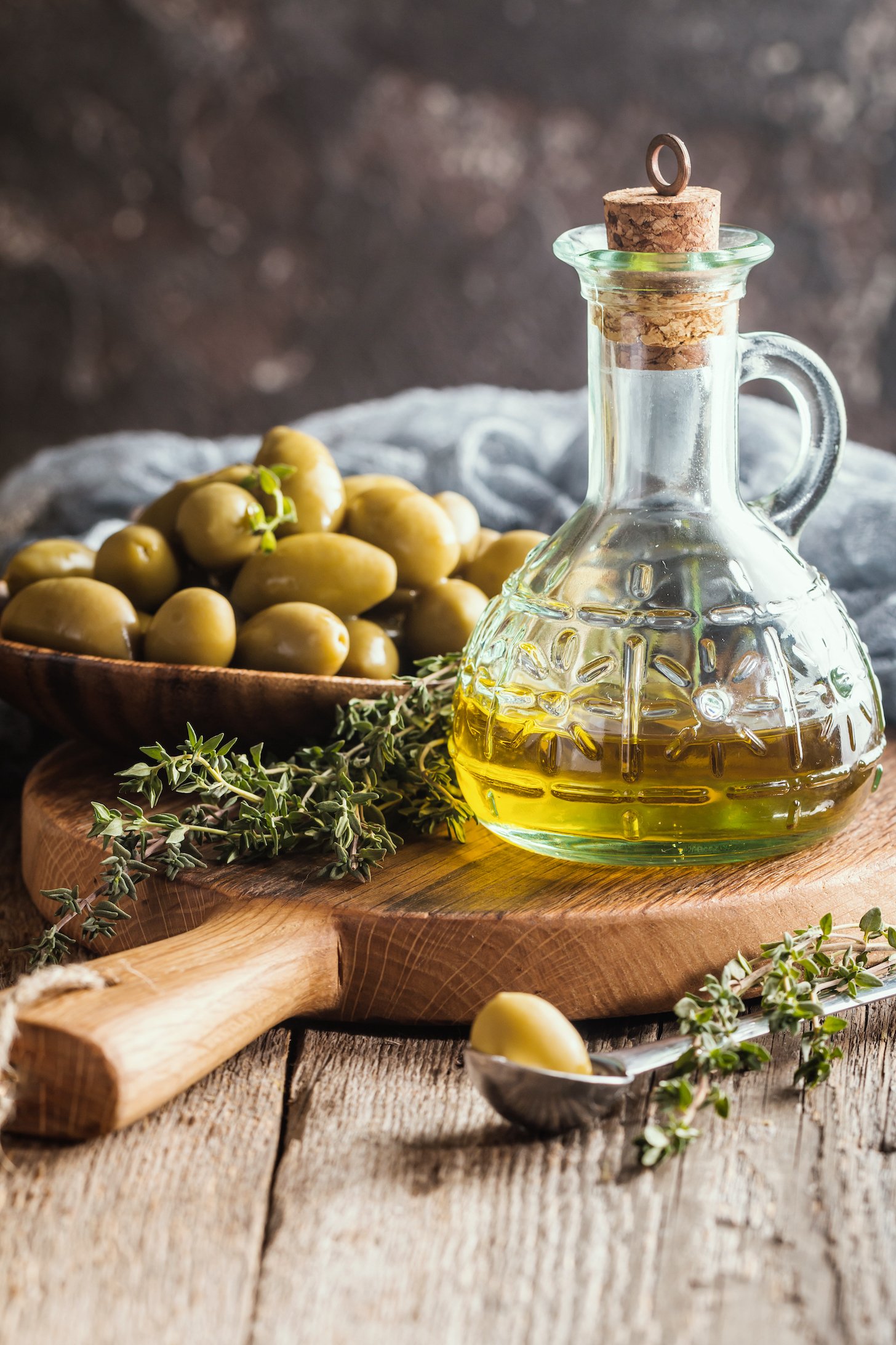 Olive oil and bowl of olives on the wooden table