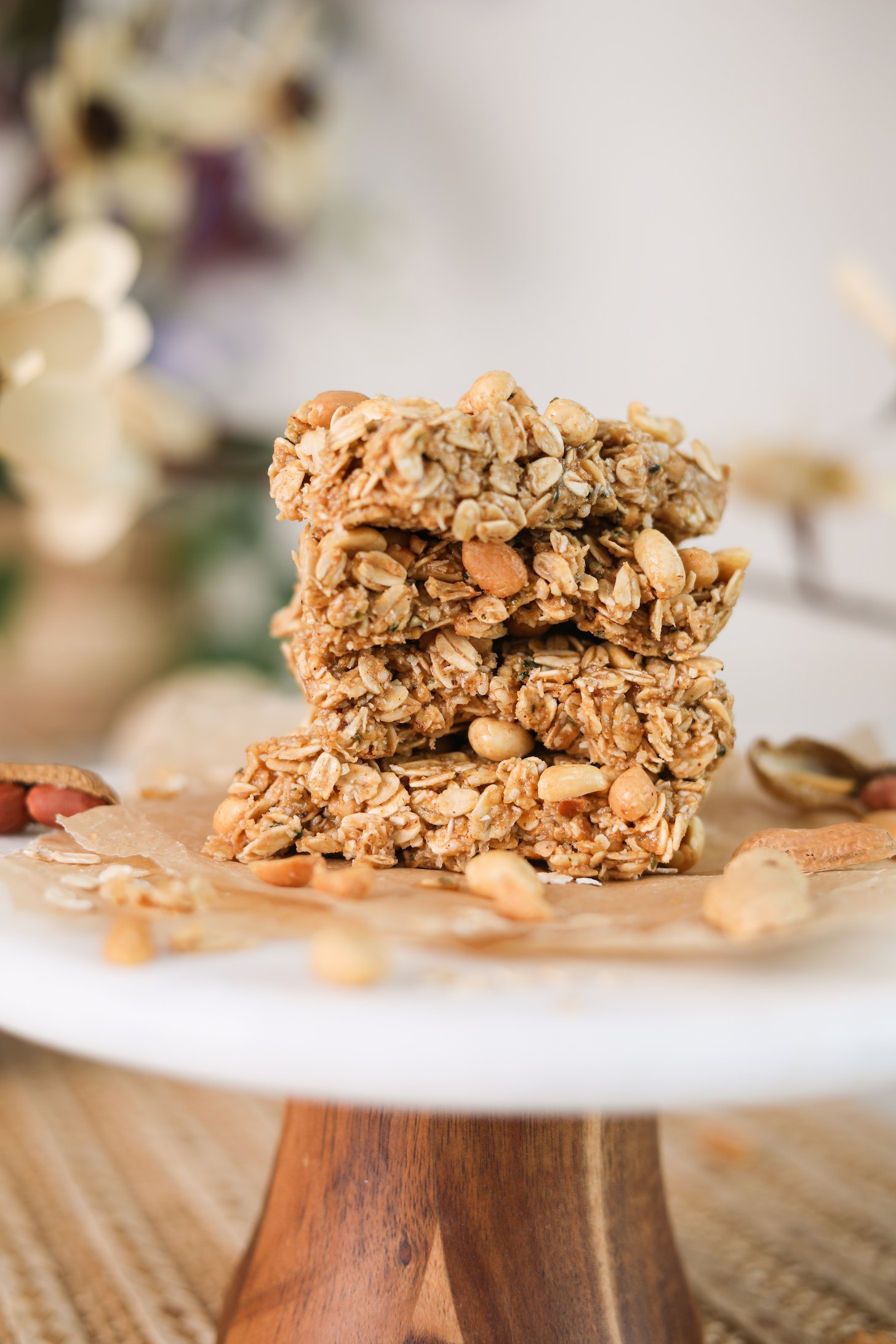 A close up image of a stack of oat bars with peanuts on a white stand.