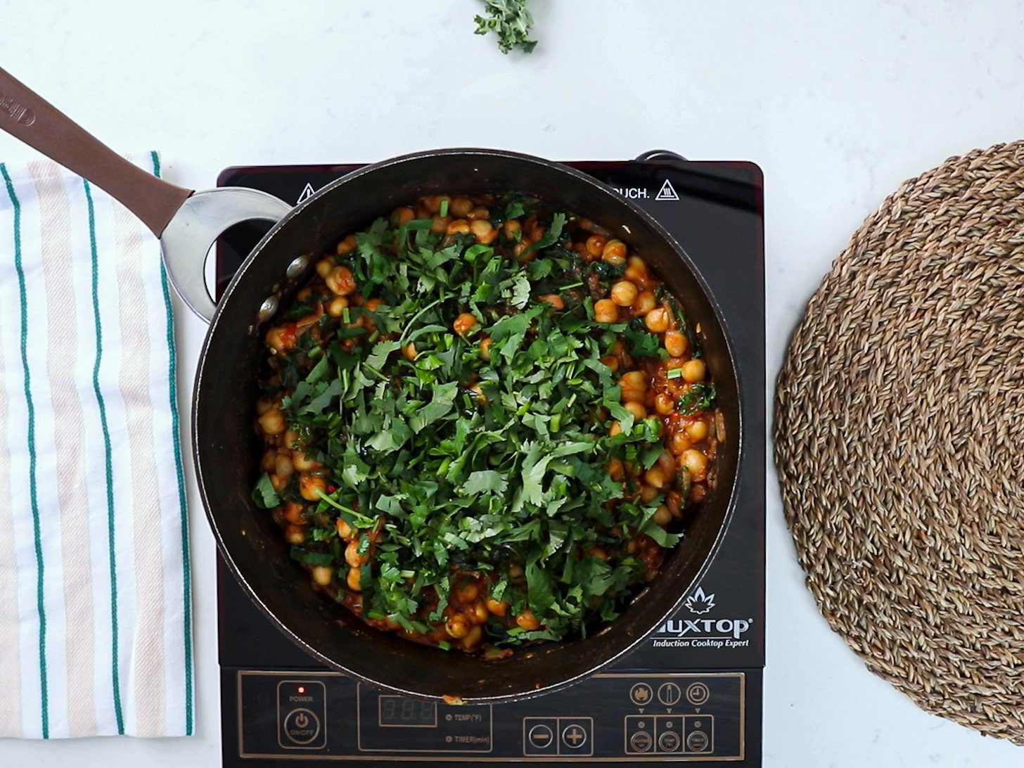 A pan of chickpea curry garnished with a generous amount of chopped fresh cilantro.