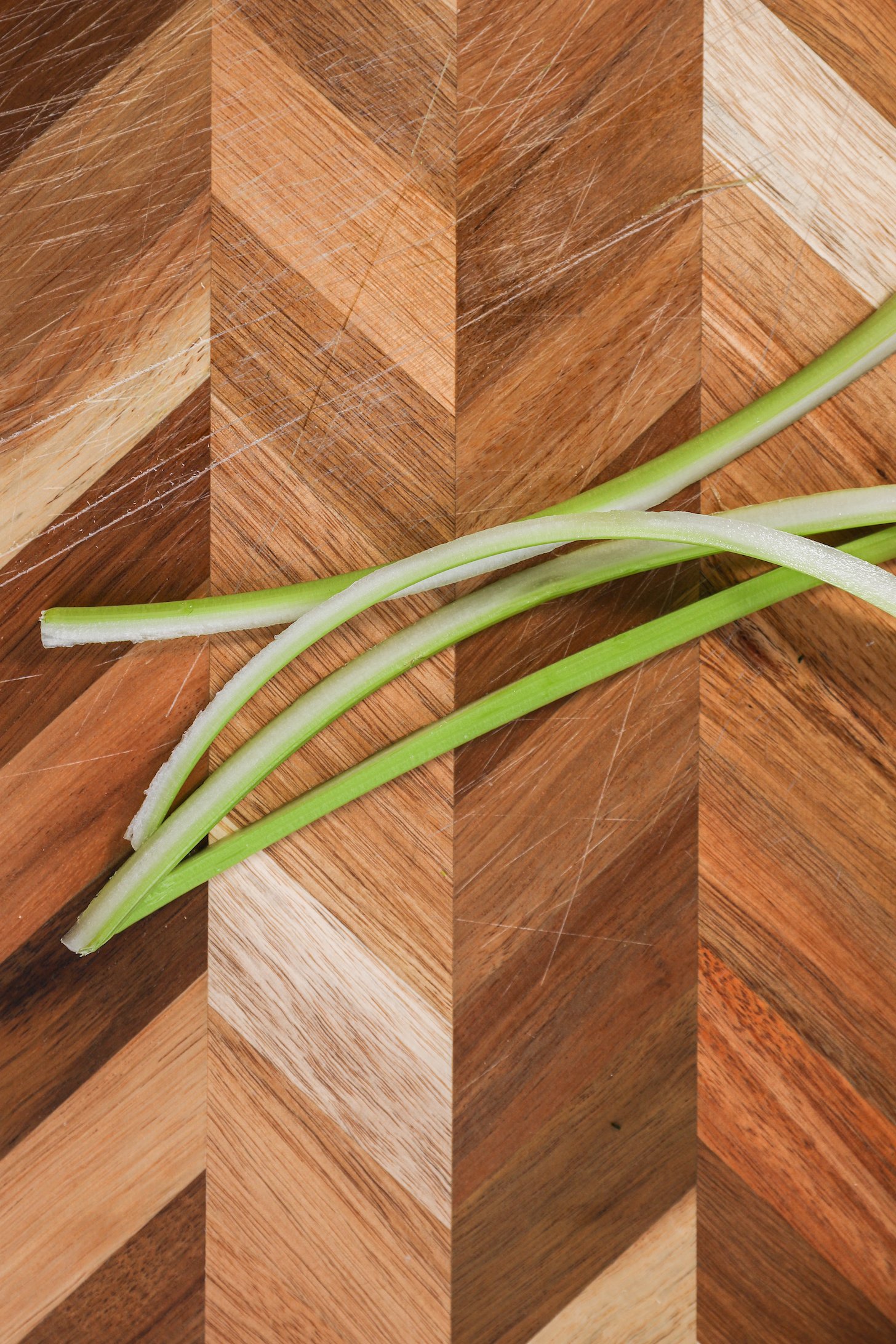 Four long strips of celery on a chopping board.