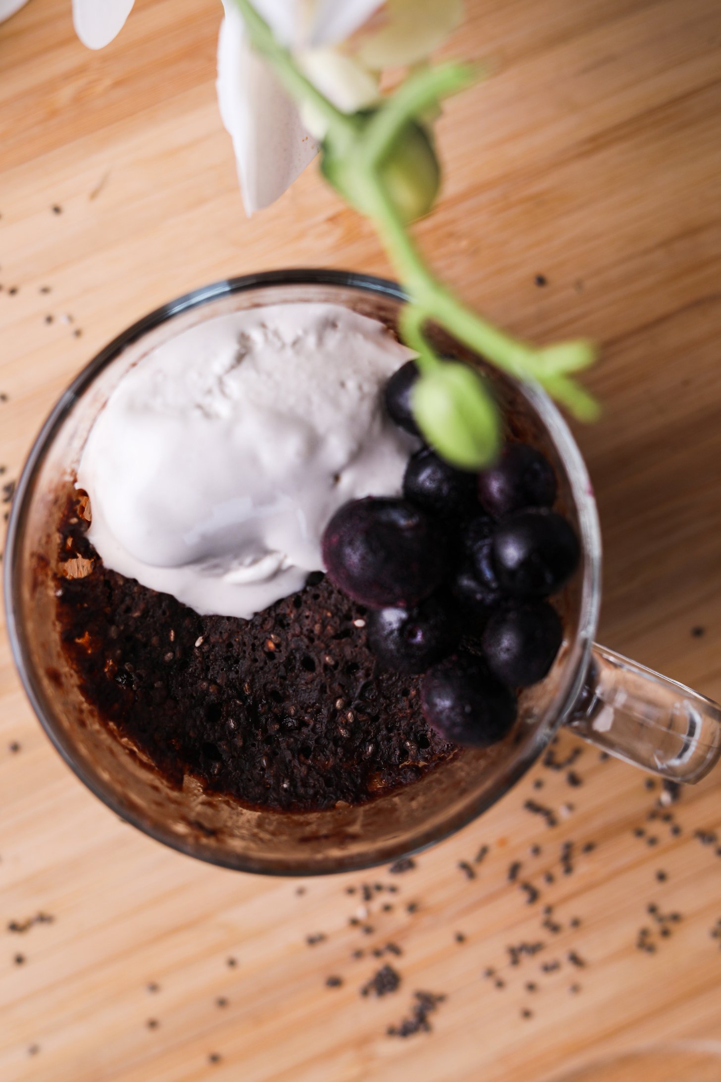 A mug of chocolate cake topped with ice cream and blueberries.