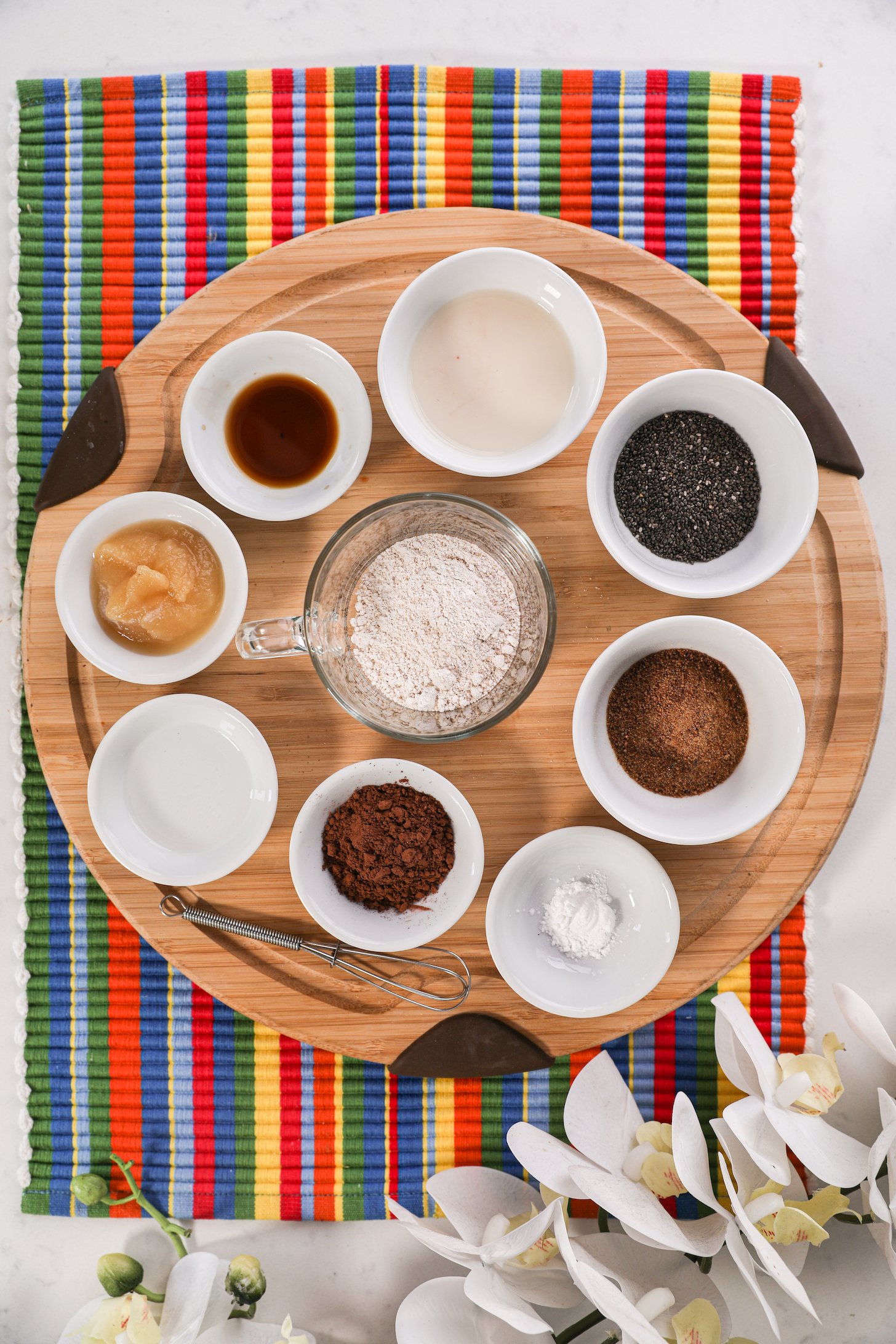 A collection of food ingredients like flour, milk, seeds, cacao displayed on a wooden board.