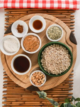 An array of food ingredients like oats, peanut butter, seeds and nuts on a wooden board.