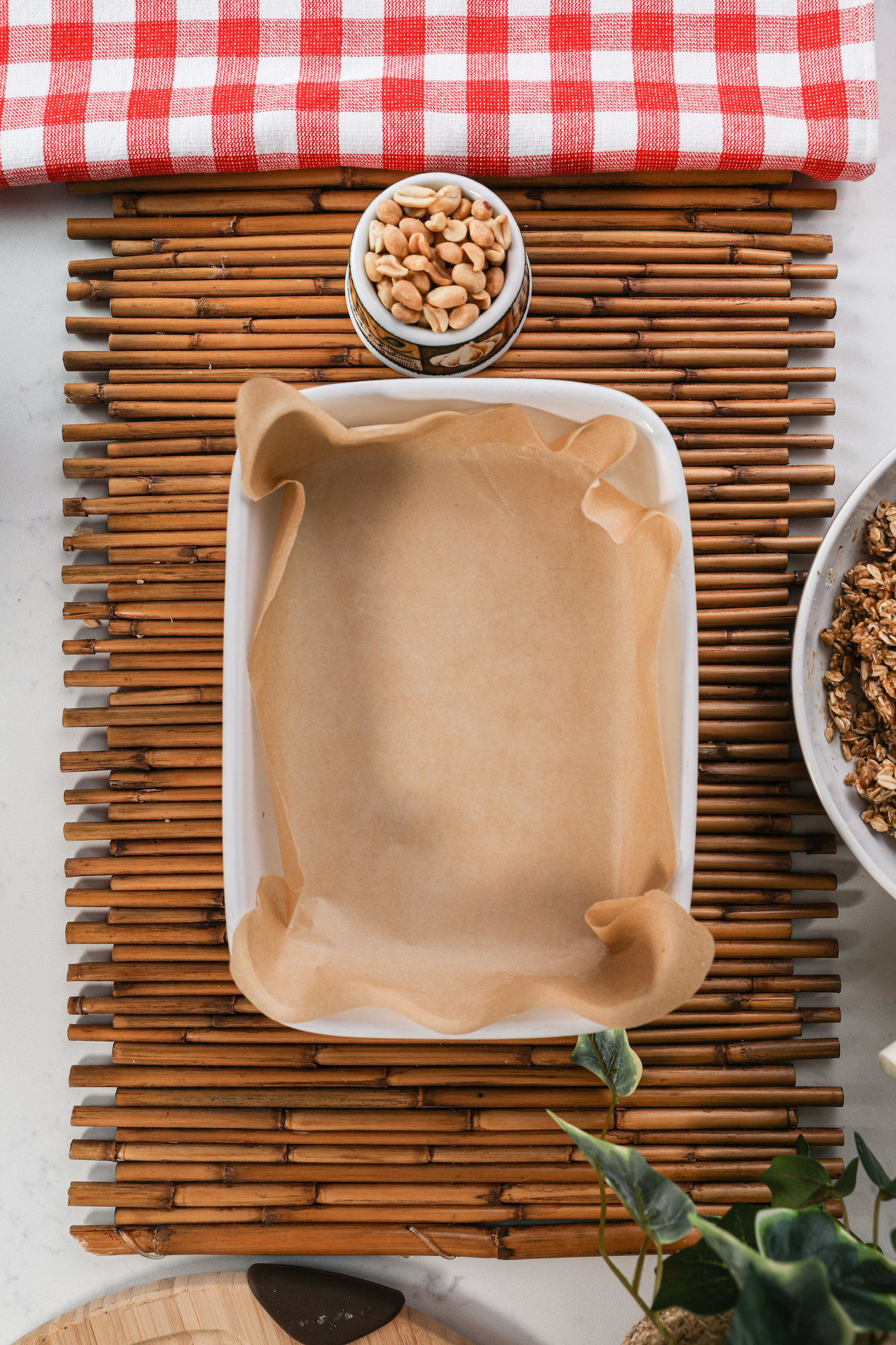 A lined pan on a wooden mat with peanuts on the side.