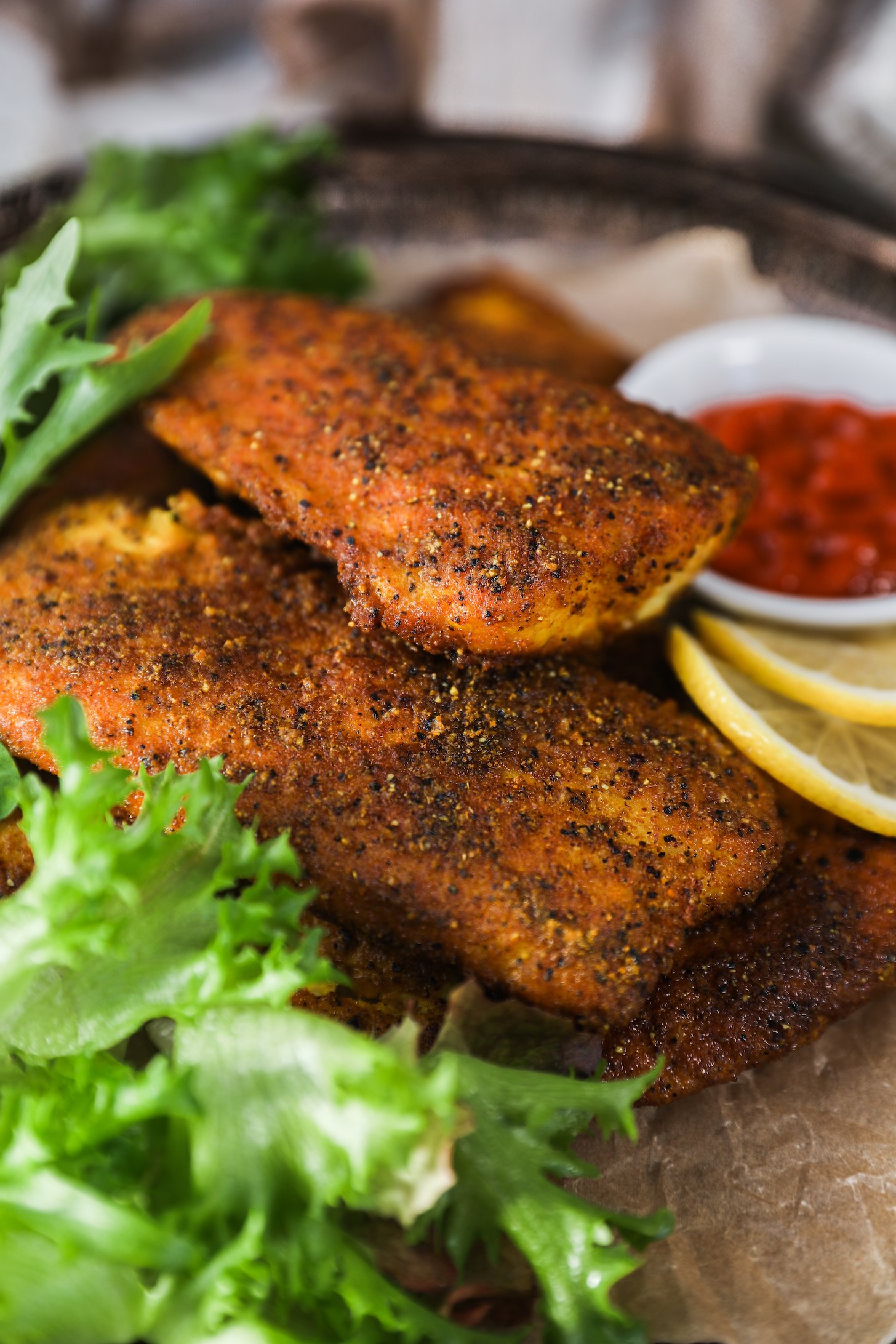 A pile of crispy fillets with lettuce and lemon slices on a tray.