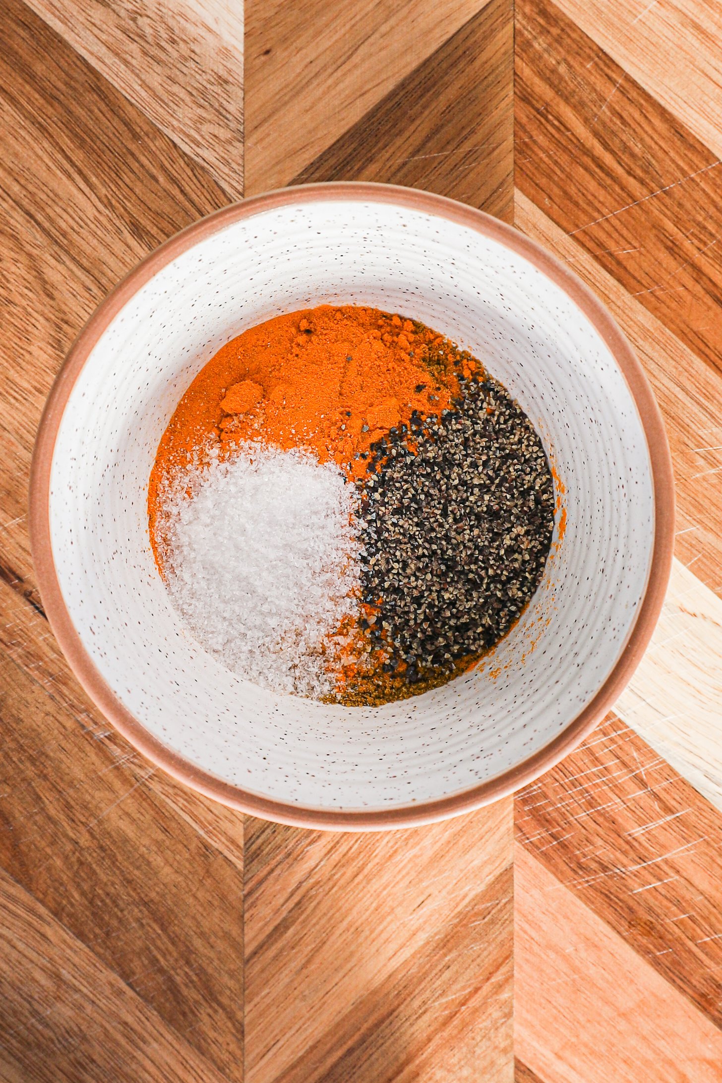 A bowl contaning a yellow spice, salt and pepper.