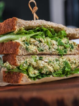 A close up angled shot of a stack of two sandwiches filled with greens and white tuna fish.