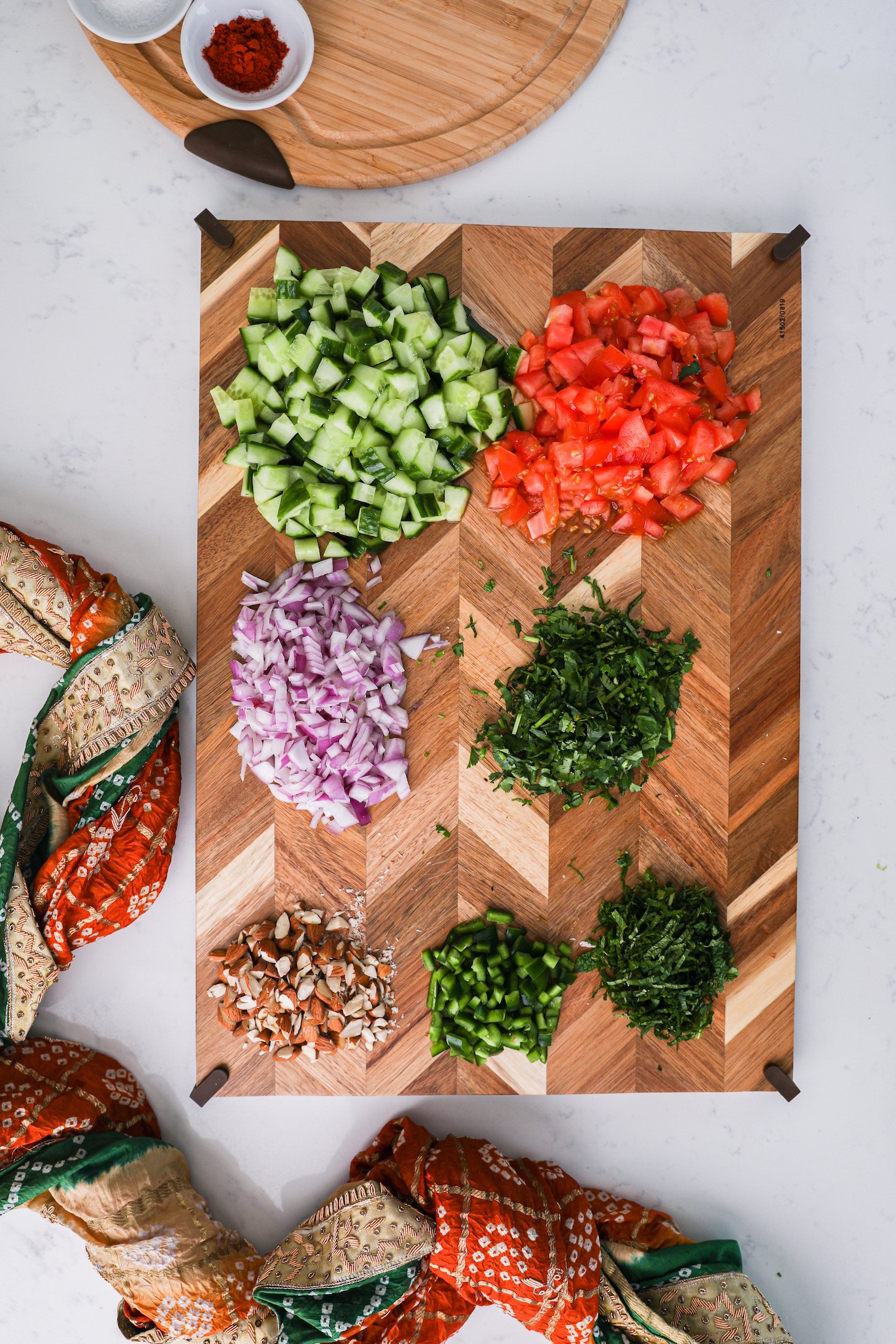 A wooden board with chopped vegetables styled around a decorative scarf.