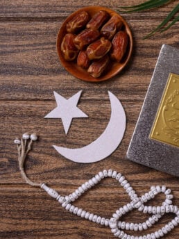 Ramadan concept with plate od dates, prayer beads and cut-out of moon and star.