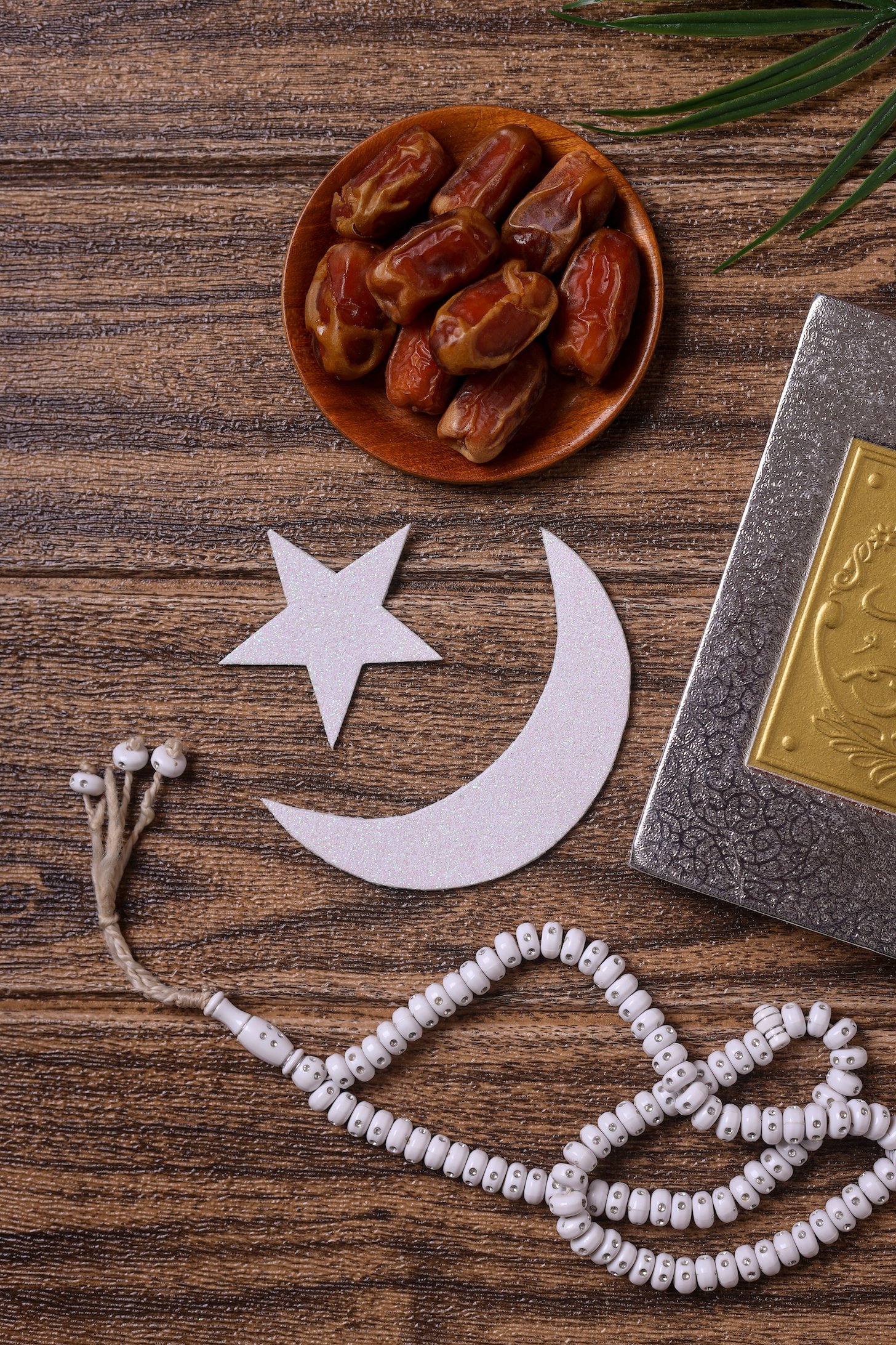 Ramadan concept with plate od dates, prayer beads and cut-out of moon and star.