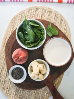 Flat lay image of food ingredients like spinach, fruit, seeds and milk.