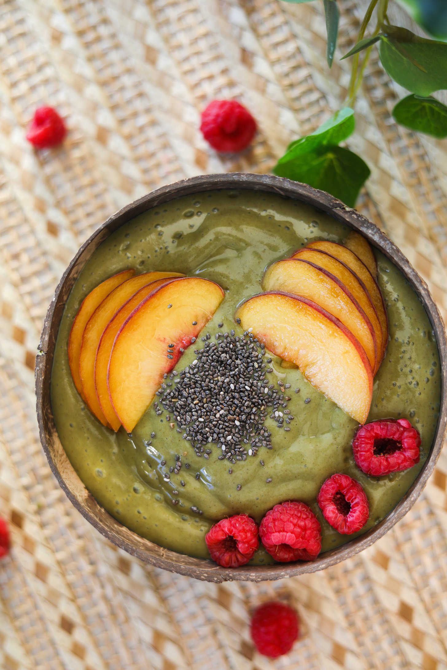 Flat lay of green smoothie bowl topped with fruit and chia seeds.