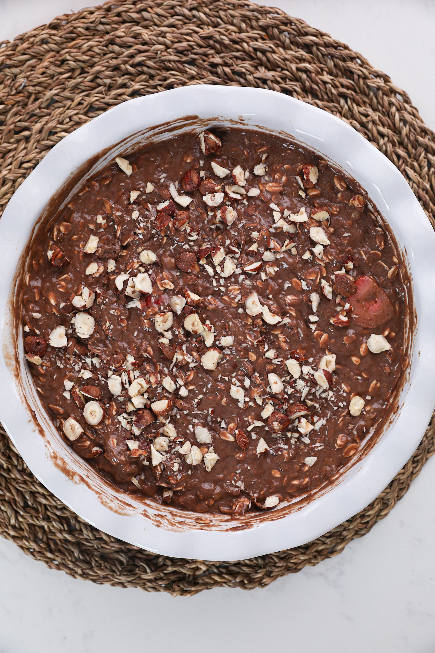 Top view of a bowl of chocolate and oats pudding topped with nuts.