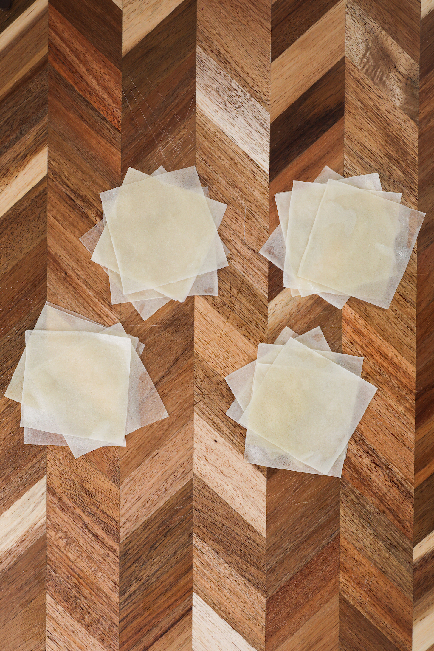 Stack of spring roll pastry sheets arranged in the shape of a flower on a wooden board.