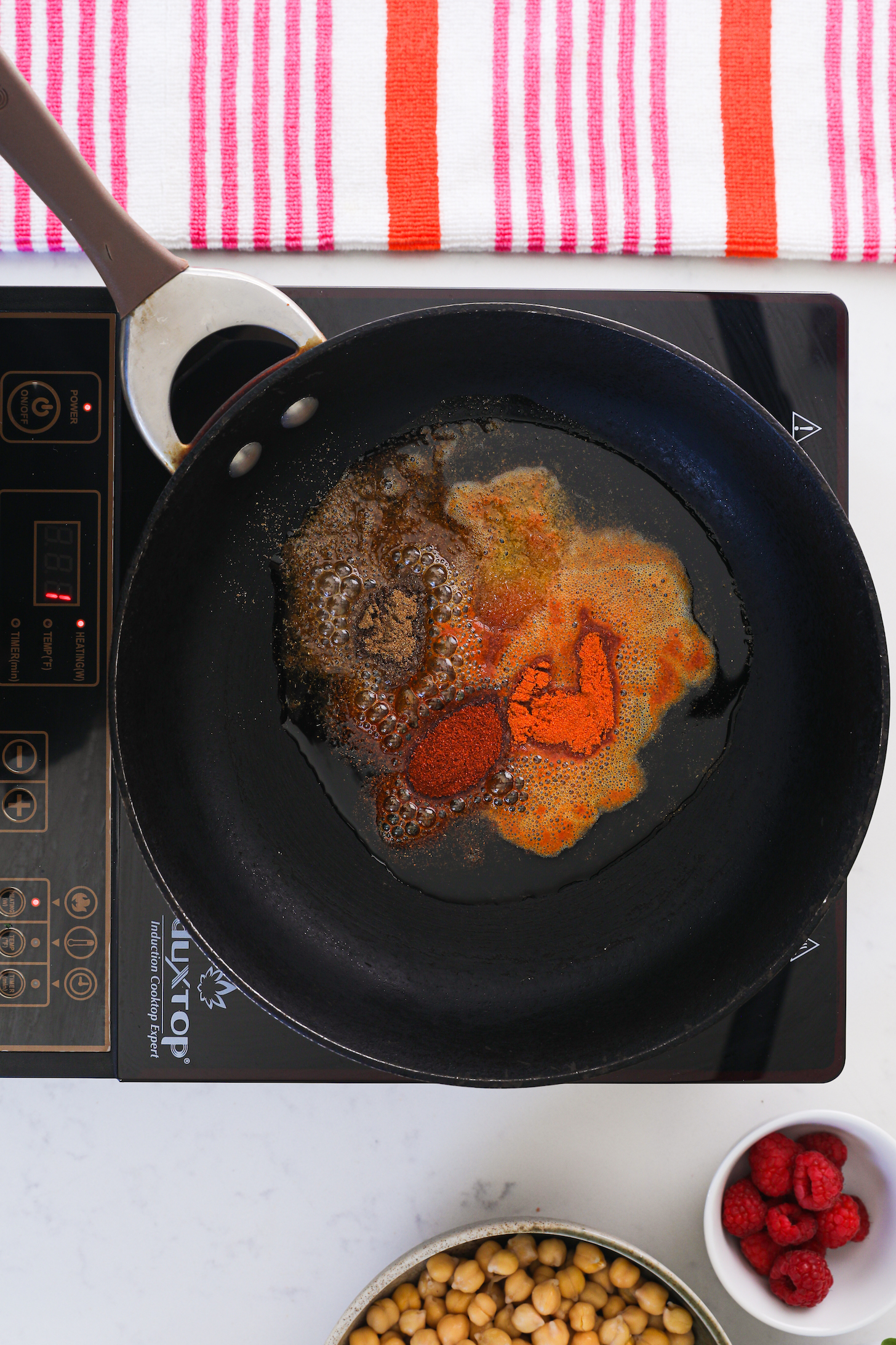 A pan on a cooktop with oil and spices.