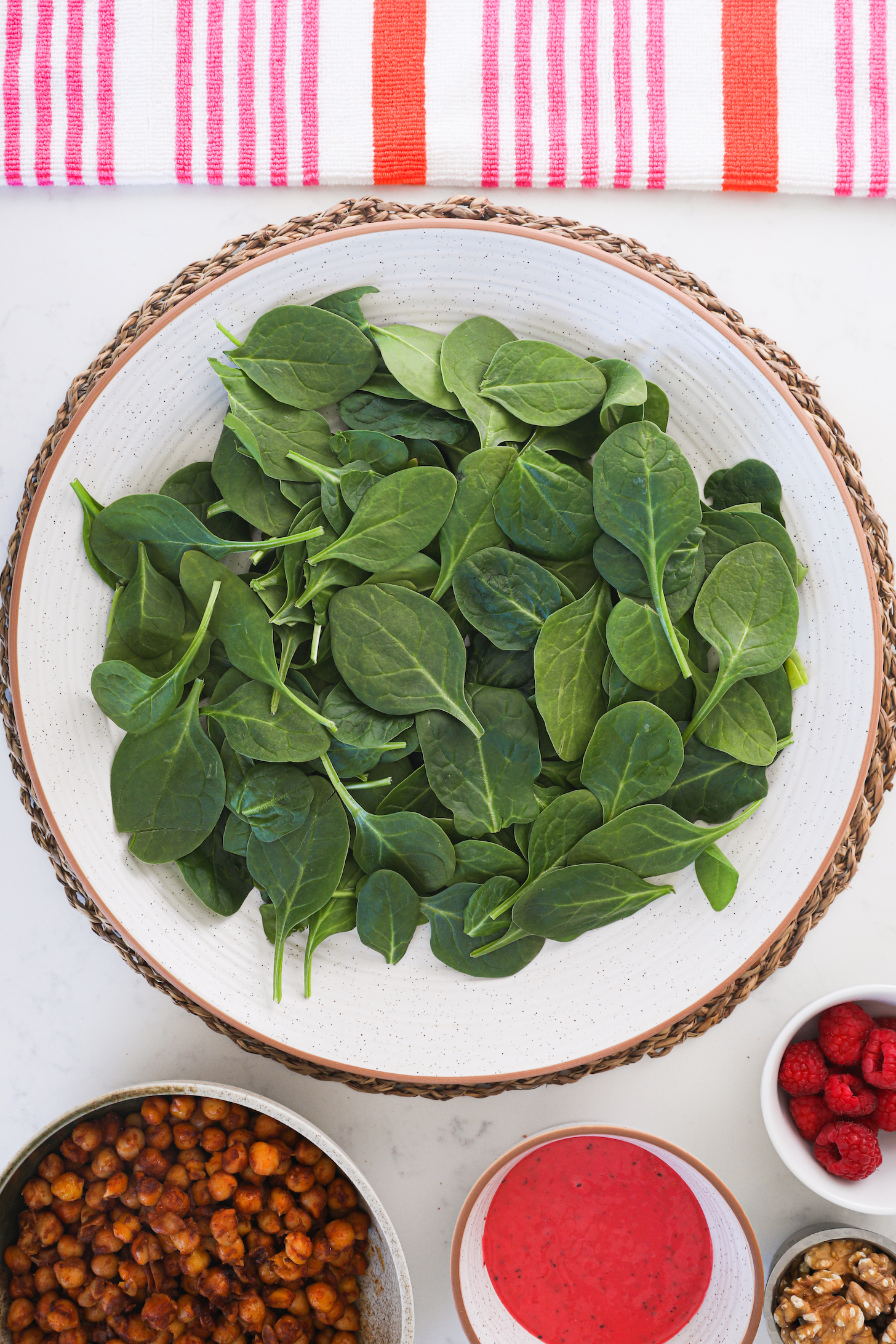 A plate of spinach leaves surrounded by bowls of food.